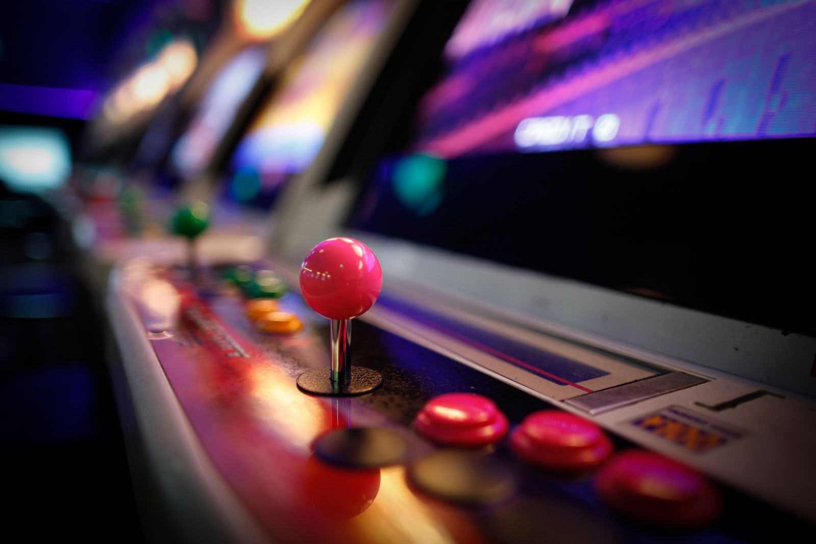 Close-up of an arcade cabinet joystick and buttons lit with neon
