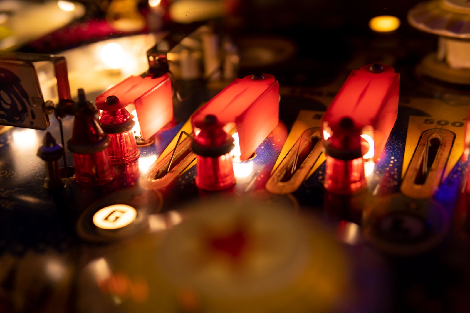 Close-up of pinball machine bumpers glowing red